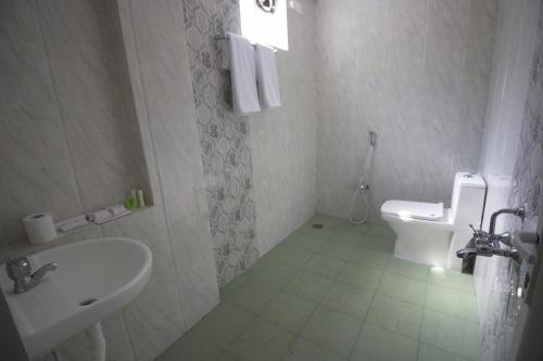 a white bathroom with a sink and a toilet at Serenity Sands Beach Resort in Puducherry