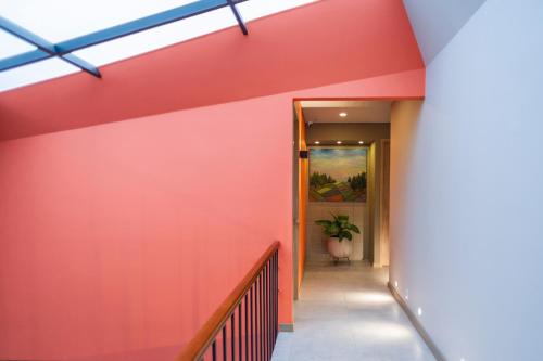 a hallway with a red wall and a staircase at Siete Balcones Hotel Coworking in Pasto