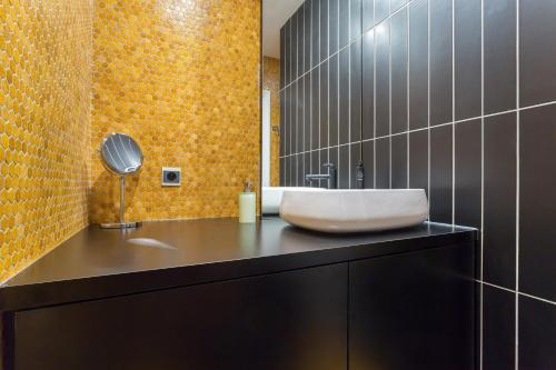 La salle de bains est pourvue d'un lavabo blanc sur un comptoir noir. dans l'établissement Stella - 2 chambres-balcon- place de la République, à Lyon