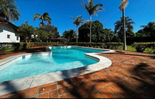 - une piscine dans une cour avec des palmiers dans l'établissement Chácara Campo Verde, à Bragança Paulista