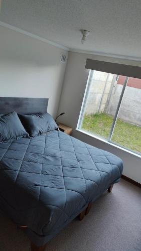 a bedroom with a bed and a large window at Casa en sector Las Mariposas in Temuco