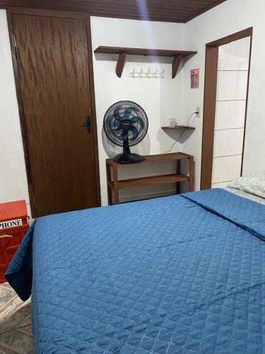 a bedroom with a blue bed and a fan at Vilarejo hospedagem in Ilha do Mel