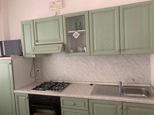 a kitchen with green cabinets and a stove and a sink at Appartamenti Belle Vacanze in Cattolica