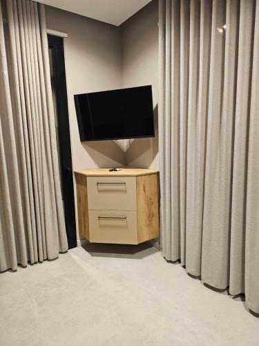 a television sitting on a stand in a room with curtains at Alfa Villa in Rrushkull