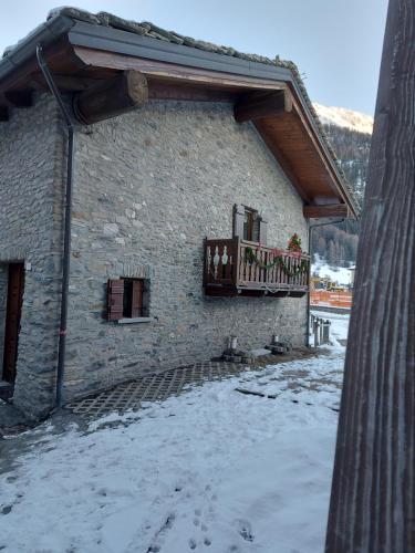 un immeuble avec un balcon avec de la neige au sol dans l'établissement Maison Sarteur Alloggio ad uso turistico -VDA-LA THUILE- 0065, à La Thuile