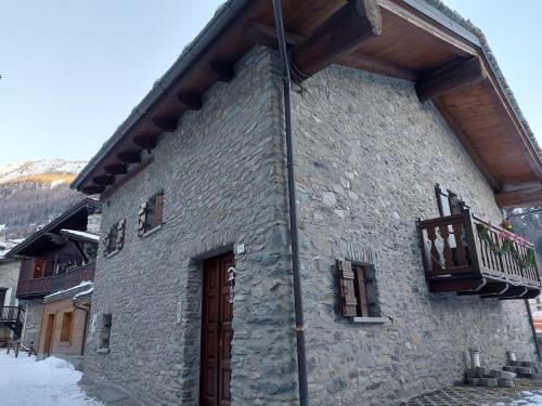 - un bâtiment en pierre avec un balcon sur le côté dans l'établissement Maison Sarteur Alloggio ad uso turistico -VDA-LA THUILE- 0065, à La Thuile