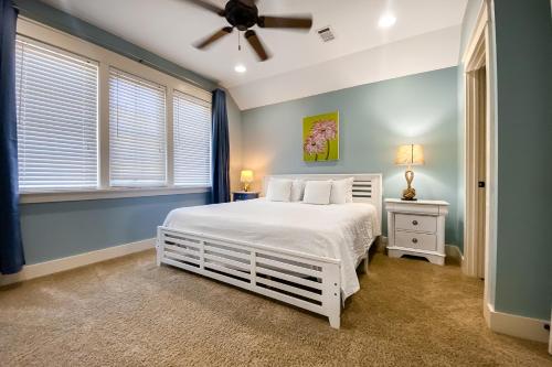 1 dormitorio con cama blanca y ventilador de techo en Barefoot Bungalo en Destin