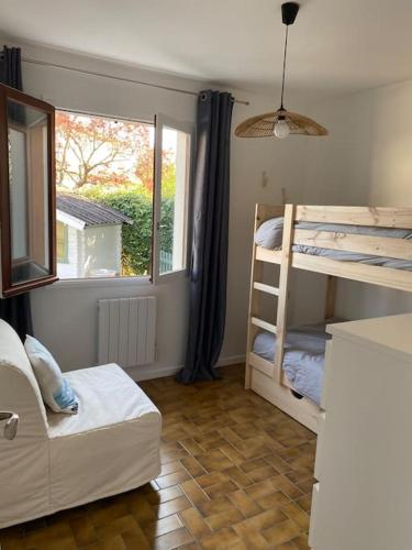 une chambre avec deux lits superposés et une fenêtre dans l'établissement Villa piscine bord de foret, à Mimizan