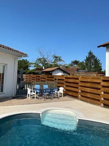 - une piscine avec des chaises, une table et une clôture dans l'établissement Villa piscine bord de foret, à Mimizan