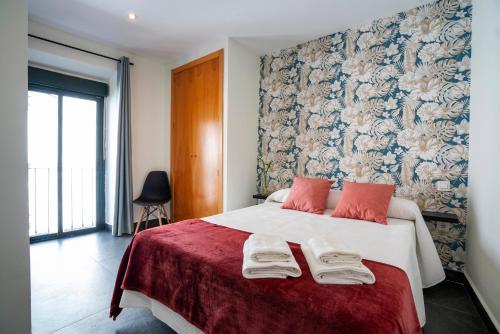 a bedroom with a large white bed with red pillows at Apartamentos Turísticos Cáceres " CENTRO HISTÓRICO " in Cáceres