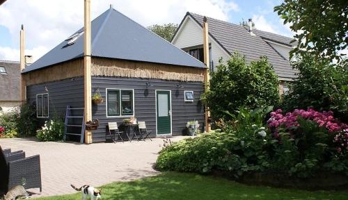a house with a dog standing in front of it at Romantisch Vakantiehuis de Hooiberg in Berkenwoude