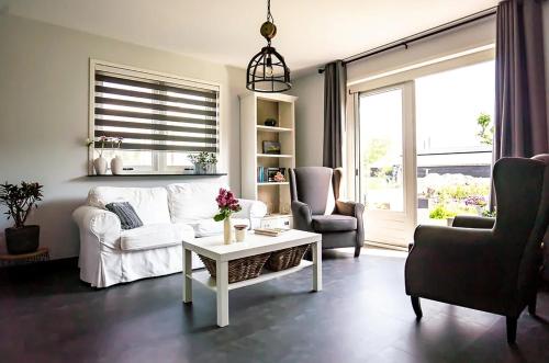 un soggiorno con un divano bianco e 2 sedie di Vakantiehuis de Hooiberg a Berkenwoude
