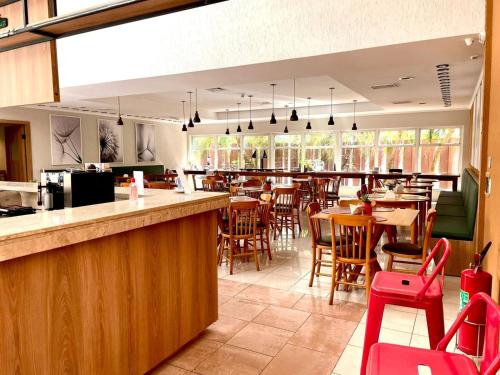 a restaurant with a bar and tables and chairs at Carlton Plaza Baobá in Taubaté