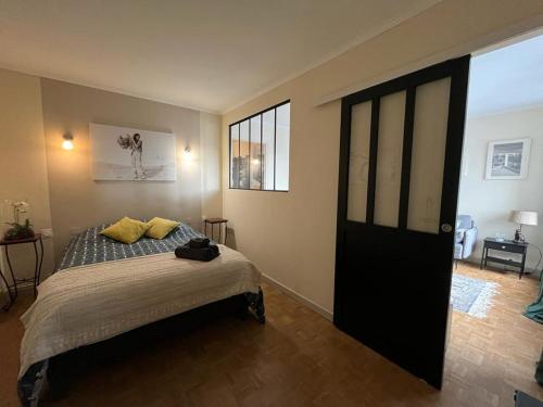 a bedroom with a bed with yellow pillows and a black door at Appartement Cosy Proche du Lac in Annecy