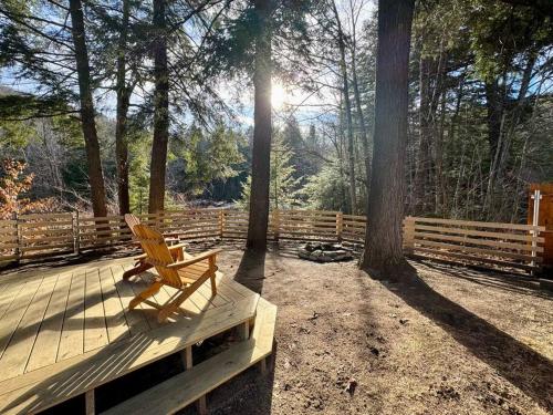 un banco de madera sentado en una terraza de madera con árboles en Brook Haven Retreat - Minutes to Mt Snow / Stratton, Pet Friendly!, en Wardsboro