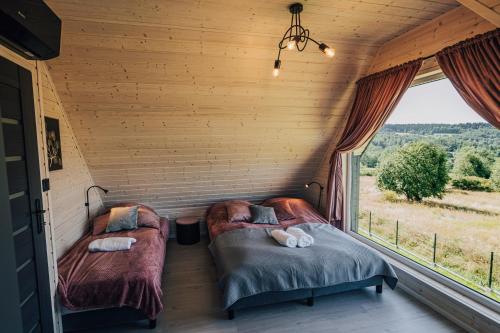 two beds in a room with a window at Ostoja pod Osówką Dom Cisza in Sierpnica