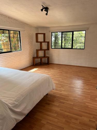 um quarto com uma cama branca e 2 janelas em Casa estrella del bosque em Coajomulco