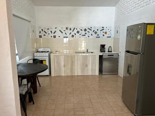 a kitchen with a table and a stainless steel refrigerator at Casa estrella del bosque in Coajomulco