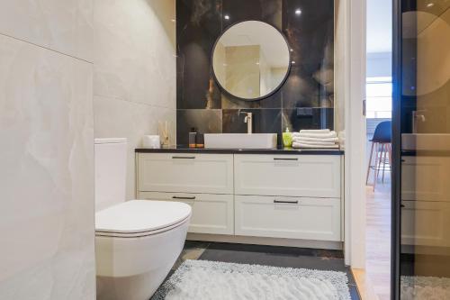 een badkamer met een wit toilet en een spiegel bij Tähe Delux Apartment in Tartu