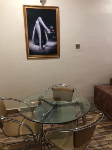 a glass table with two chairs and a picture on the wall at Blue-View Hotel and Apartments Riverpark in Rubuchi