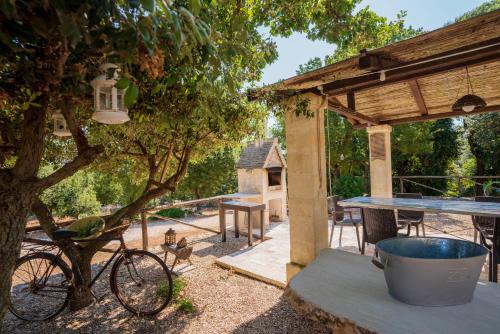 a patio with a table and a bike under a tree at Trullo Mont Bell con giardino e piscina privata in Selva di Fasano