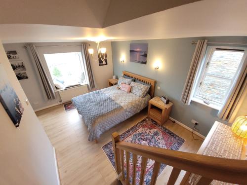 a small bedroom with a bed and two windows at Looe, Cornwall, Langunnett Cottage in Looe