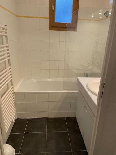 une salle de bain blanche avec une baignoire et un lavabo dans l'établissement Charmant appartement T3 avec magnifique vue, à Saint-Gervais-les-Bains