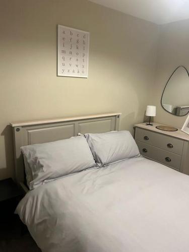 um quarto com uma cama branca e um espelho em Comfortable & Spacious Apartment em Stoke-on-Trent