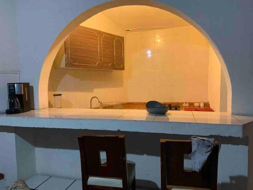 a kitchen with an archway over a counter with two chairs at DEPARTAMENTO VISTA BELLA MIRADOR in Morelia