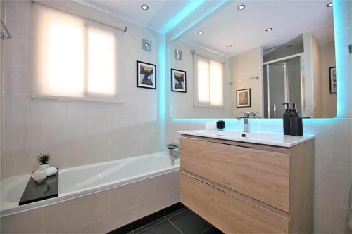 een badkamer met een bad, een wastafel en een spiegel bij Beachhouse GALORE in Estepona