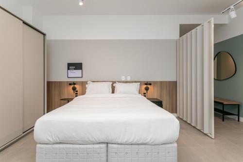 une chambre avec un grand lit blanc dans une pièce dans l'établissement Studios Tower by Viva - Prédio com piscina e estacionamento no centro de Floripa, à Florianópolis