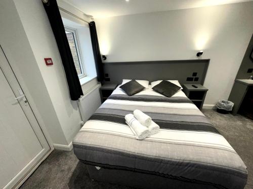a bedroom with a large bed with two pillows at Gainsborough Lodge in Horley
