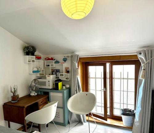 una cocina con 2 sillas blancas y una mesa en Mini studio 12m2, Lyon4, centre CroixRousse, 2prs en Lyon