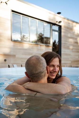 un homme et une femme dans une piscine dans l'établissement Pépiite Terre de Provence - Lodge nature & spa, à Châteaurenard