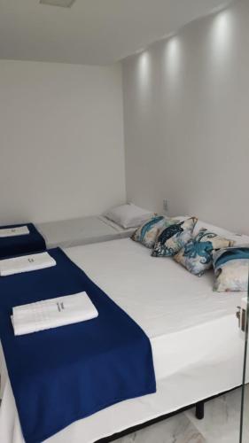 a white bed with a blue blanket on it at Oceano Residence in Búzios