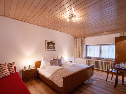 1 dormitorio con 1 cama grande y 1 sofá rojo en Bauernhof Hanslingerhof, en Wörgl