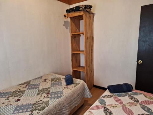 a room with two beds and a book shelf at Cabañas puna poho in Hanga Roa