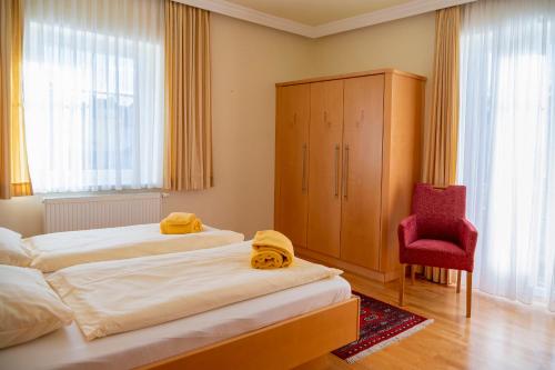 a bedroom with two beds and a red chair at Sonnblick am Wörthersee in Pörtschach am Wörthersee