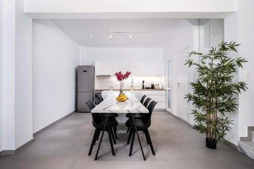 a white dining room with a white table and black chairs at Casa Lemonia 2 Min walking to BEACH in Kardamaina