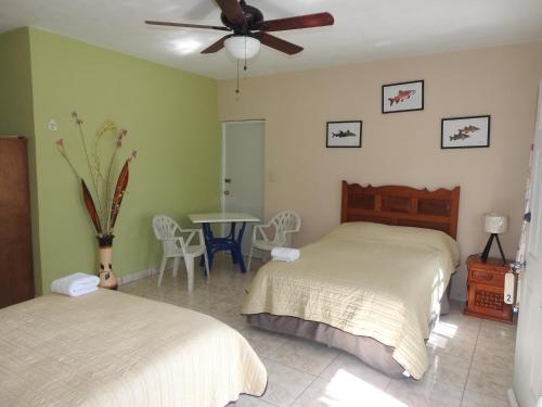 a bedroom with two beds and a table and a ceiling fan at Las Palapas de Punta Allen in Punta Allen