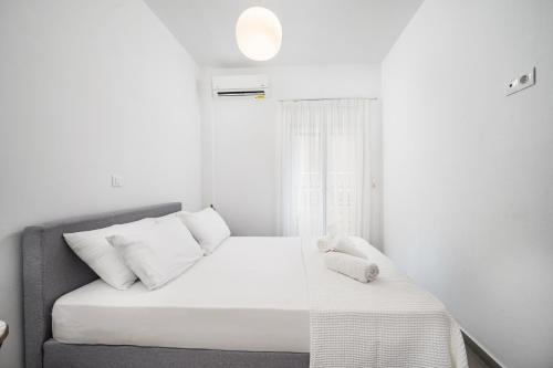 a white bedroom with a bed and a window at Casa Lemonia - 110 sqm Maisonette in Kardamaina