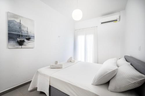 a white bedroom with a bed and a picture on the wall at Casa Lemonia - 110 sqm Maisonette in Kardamaina