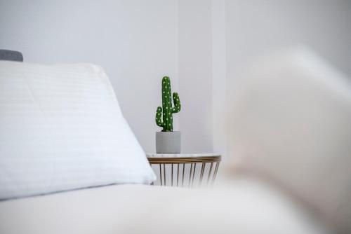 a white bed with a cactus on a side table at Casa Lemonia - 110 sqm Maisonette in Kardamaina