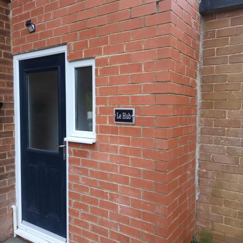 uma parede de tijolos com uma placa ao lado de uma porta em Le Hub - Roundhay Leeds - 1-Bed Studio & Ensuite em Leeds