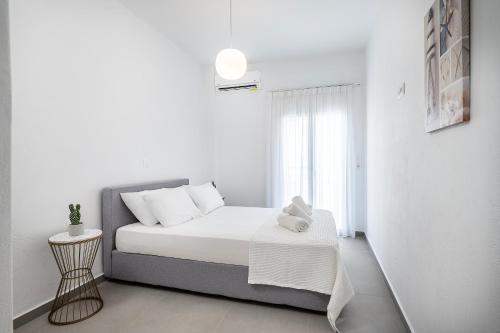 a white bedroom with a bed and a window at Casa Lemonia - 110 sqm Maisonette in Kardamaina