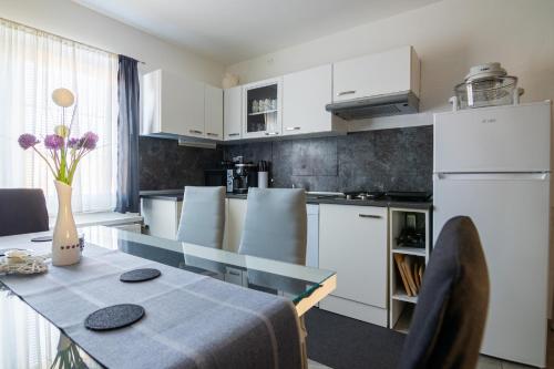 a kitchen with white cabinets and a table with purple flowers at Apartma Ella in Lovrenc na Pohorju