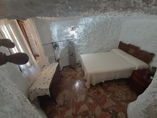 um pequeno quarto com uma cama e uma janela em Casa Cueva "El Mirador de Piedra" em Pegalajar
