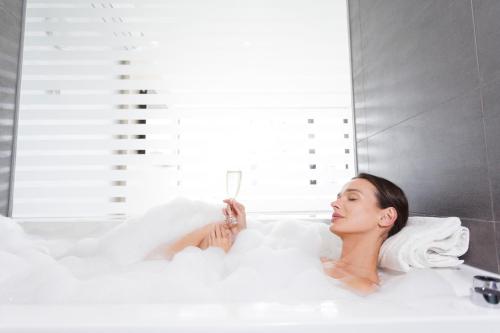 a woman laying in a bathtub in a bathroom at Pullman Vina del Mar San Martin in Viña del Mar