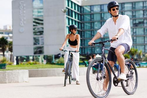 a man and a woman riding bikes in a city at Pullman Vina del Mar San Martin in Viña del Mar