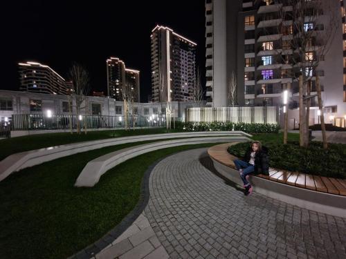 a person sitting on a bench in a park at night at Beograd na vodi - BW AURORA LUXURY in Belgrade
